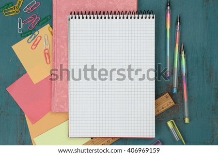 Office set with notebooks, colored pens and clips on blue wooden background