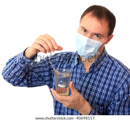 A man in a medical mask dissolves a pill in glass of water.