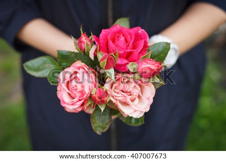Closeup of woman's hand holding beautiful bunch of garden roses. View from above, selective focus on flowers.
