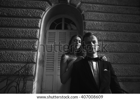 Happy beautiful newlyweds posing near the old building b&w