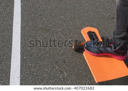 foot longboard asphalt. Pink sneaker on a longboard on paving road