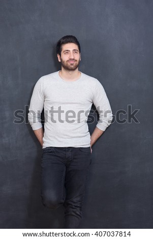 Handsome and confident. Handsome young man  smiling while standing against grey background