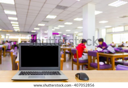 Laptop on the table,blur image of library as background.