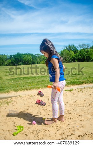 A  picture of little girl playing sand at public park ,filtered color tone in picture.