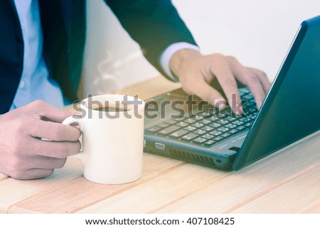 Businessman relaxing by coffee cup while working.