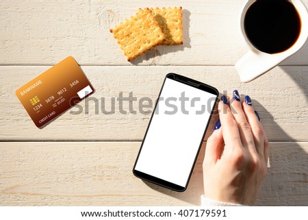 A woman sitting at a white wooden table and pay for purchases via smartphone
