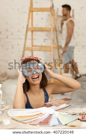Young woman laughing in protective eyewear at home renovation.
