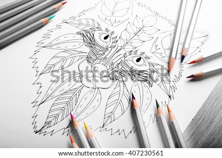 Adult anti stress coloring and crayons on wooden table closeup