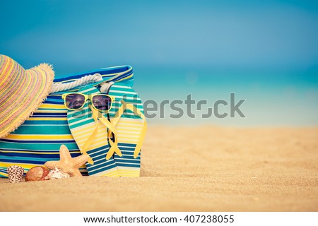 Flip-flops and bag on sandy beach against blue sea and sky background. Summer vacation concept