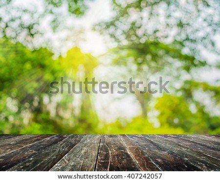 wood table and blur image of Abstract Bokeh of tree green color background.