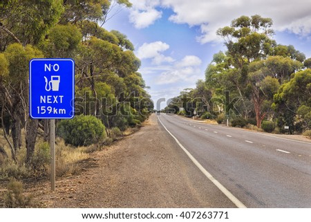 No fuel sign along Eyre Highway in South Australia. Natural eucalyptus woods without developed infrastructure and motoring service under blue cloudy sky