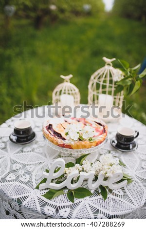 Engagement photo session. Love story. Decorated table with cherry pie and wooden sign Love
