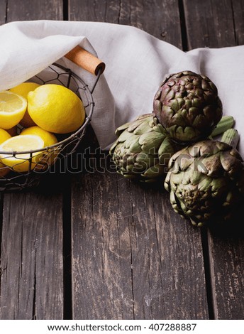 Ripe Organic Artichokes on the rustic wooden board  with lemon, napkin and knife