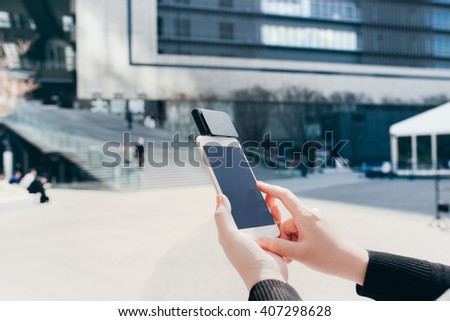 Woman use of mobile phone to pay. Using Card Reader outdoors in the city