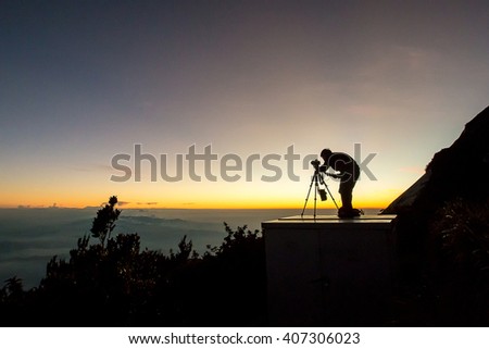 Silhouette of a photographer framing a shot, taking pictures at beautiful sunset on Laban Rata.This place is for climbers to rest before summiting the mount Kinabalu peak.