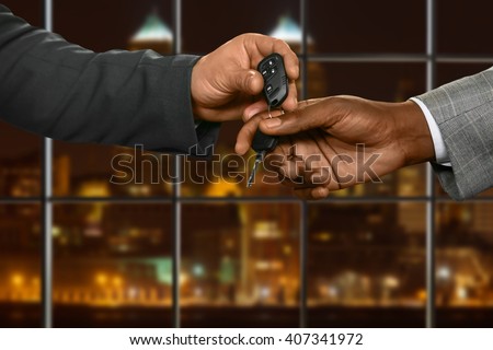 Businessman gives car key away. Men passing key at night. Ready for a test-drive. Sign of trust.
