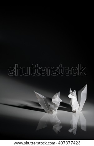 Two squirrels origami made of white paper isolated on black background.
