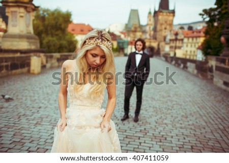 Beautiful blonde bride & handsome groom posing on Prague bridge, honeymoon