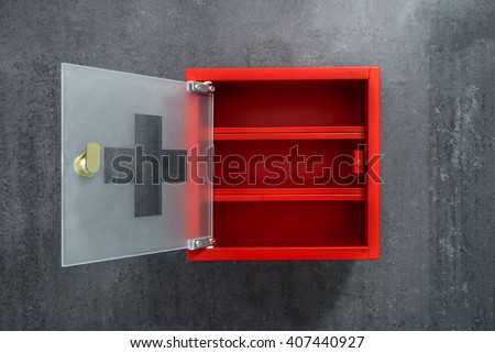 Open red metal empty medicine cabinet hanging on a dark gray marble wall background. Front view