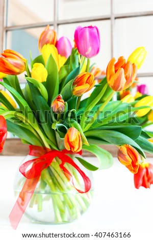 Bouquet of spring colorful tulip flowers in glass vase. Summertime indoors vertical closeup image