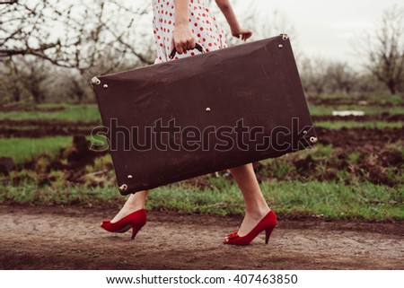 Details of woman holding retro suitcase in field