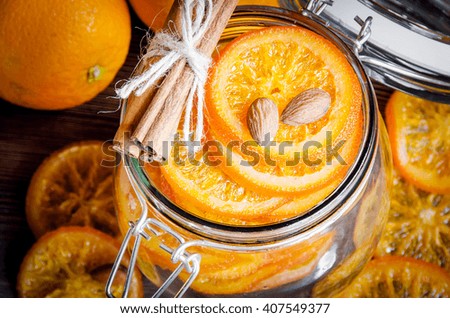 Candied oranges in a glass jar, cinnamon sticks and almond, shot from above, closeup