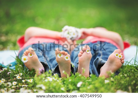 Happy little children, lying in the grass, barefoot, daisies around them, playing happily, childhood happiness concept