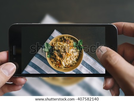 Taking picture of fried rice bowl with mobile phone in male hands.Vintage style.
