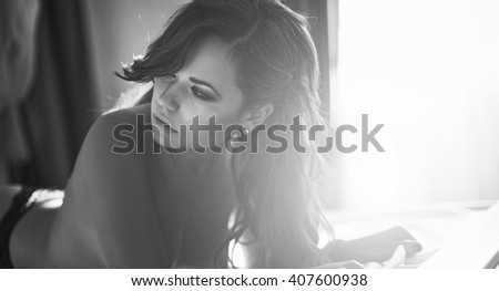 young girl in the early morning luxuriating in bed in the morning summer sun. dressed in blue underwear, a light beam is on it. Luxuriously her healthy long hair a bit disheveled.