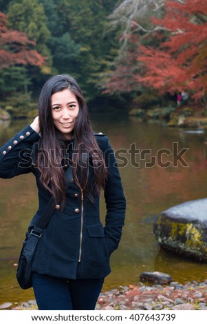 Beautiful young girl portrait in a park with a lake in Autumn Season. Happy Asian Girl in a park during Autumn season. Portrait of a young Asian woman with autumn trees on the background. 