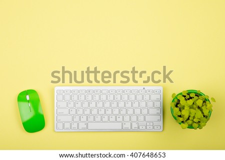 Wireless slim white keyboard and green mouse on yellow background