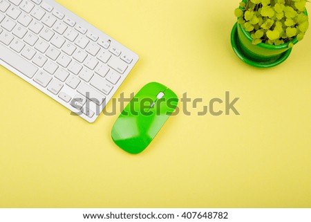 Wireless slim white keyboard and green mouse on yellow background