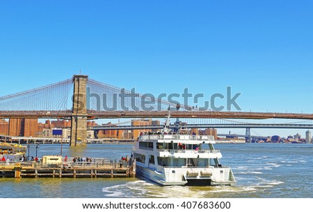Ferry boat and and Brooklyn bridge above East River, New York, USA. Brooklyn Bridge is among the oldest bridges in the USA. Manhattan on the background. Tourists on the boat and on the pier.
