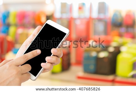 woman use mobile phone and blurred image of luggage shop in the mall  for background