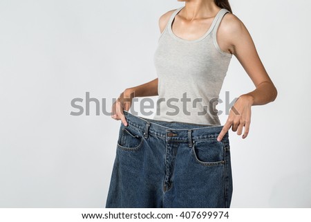 A picture of a young woman in loose jeans showing effects of diet her body