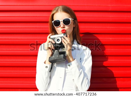 Pretty cool woman with retro camera over red background
