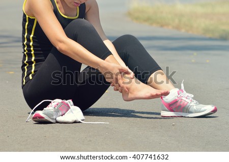  Young woman suffering from an ankle injury while exercising and running Royalty-Free Stock Photo #407741632