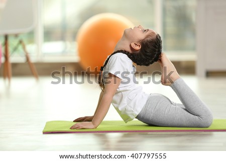 Little cute girl practicing yoga pose on a mat indoor Royalty-Free Stock Photo #407797555