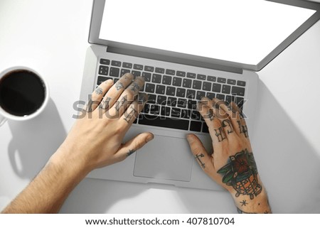 Young man with tattoo using laptop at the table at home