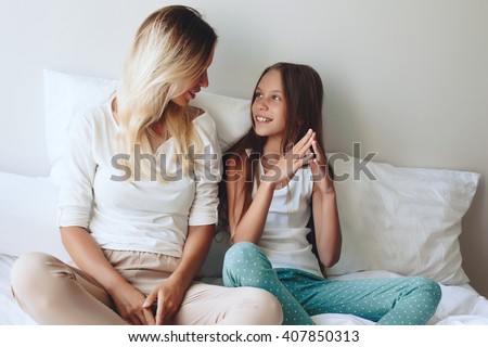 Mom with her tween daughter relaxing in bed, positive feelings, good relations. Royalty-Free Stock Photo #407850313