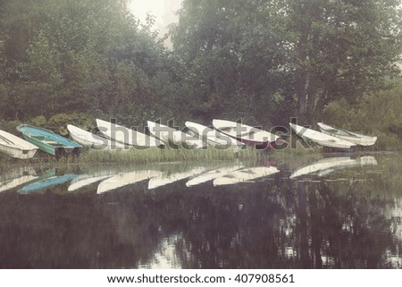 Rowing boats on the shore. Image taken on a cold and foggy morning. Water reflects nicely the boats. Image has a vintage effect applied.