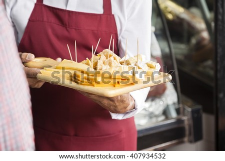 Salesman Holding Cutting Board With Assorted Cheese Royalty-Free Stock Photo #407934532