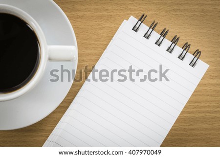 Cup of coffee on wood table and notepad