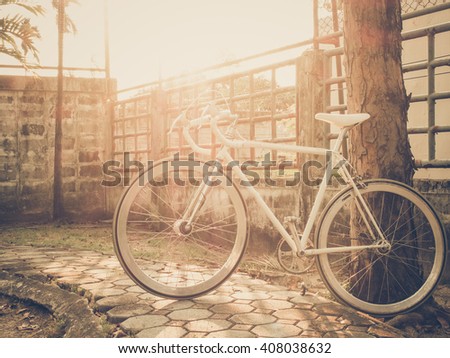 White sport bicycle in summer grass field with sunlight background. Photo in old image color and vintage style.
