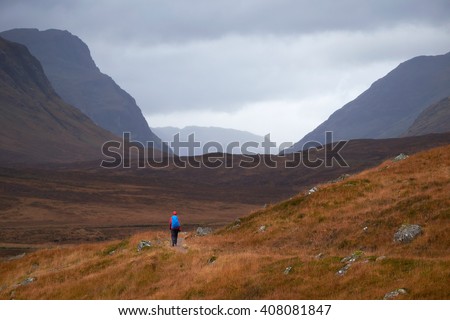 A hiker walking along the West Highland way into Glencoe, Scottish Highlands. Royalty-Free Stock Photo #408081847