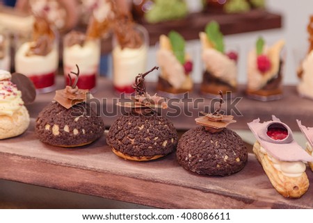 French patisserie. Chocolate choux pastries on wooden stand in confectionery shop