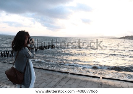 A woman taking photo of sunset into the lake