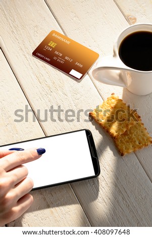A woman sitting at a white wooden table and pay for purchases via smartphone