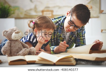 children brother and sister, boy and girl reading a book at home Royalty-Free Stock Photo #408140377