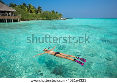 Woman snorkeling in clear tropical waters in front of exotic island